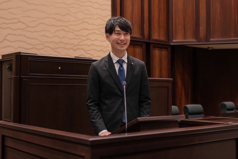 三郷市議会の議場で発言する鈴木優作