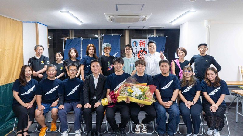 選挙事務所で支えてくれた人たちと並ぶ鈴木優作